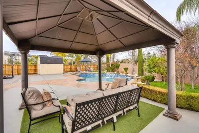 a swing under a large umbrella on a patio at Outdoor Oasis and Hot Tub! Spacious Clovis Home in Clovis