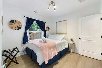 a bedroom with a bed with blue curtains and a window at East Sac Getaway, Walking Distance to Hospitals in Sacramento