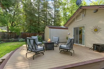 a wooden deck with chairs and a table with a fire at East Sac Getaway, Walking Distance to Hospitals in Sacramento