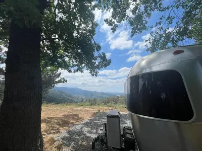 a close up of a camper parked next to a tree at Modern Airstream with amazing view - 10 to 15 minutes from Kings Canyon National Park in Dunlap