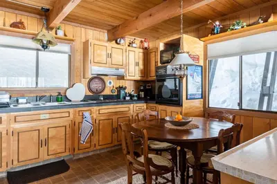 a kitchen with wooden cabinets and a table with chairs at Quaint Cabin in Serene Lakes - Close to Skiing! in Soda Springs