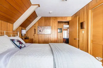 a large white bed in a room with wooden walls at Quaint Cabin in Serene Lakes - Close to Skiing! in Soda Springs