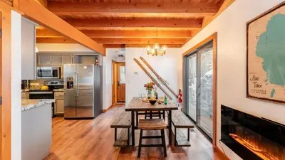 a kitchen with a table and a refrigerator at Minutes to Skiing Lake Hot Tub Fire Pit Deck Indigo Owl by AvantStay in Homewood
