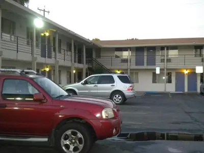 two cars parked in a parking lot in front of a building at Wasco Inn in Wasco