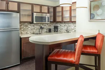 a kitchen with a counter and two chairs at a kitchen island at Staybridge Suites Sacramento-Folsom by IHG in Folsom