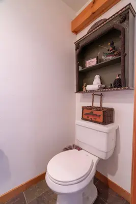 a bathroom with a toilet with a shelf above it at Hideaway Down Canyon #101 in June Lake