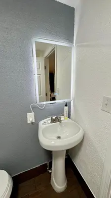 a bathroom with a white sink and a mirror at Budget Motel in Gilroy