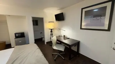 a hotel room with a desk and a bed and a bed and a desk at Budget Motel in Gilroy