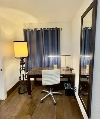 a desk with a lamp and a chair in a room at Budget Motel in Gilroy