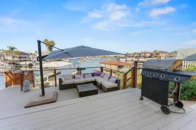 a grill on a deck with a couch and an umbrella at * Large Updated Waterfront Delta Manor Boat Dock * in Discovery Bay