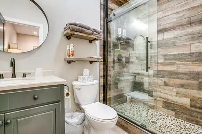 a bathroom with a shower and a toilet and a sink at Game Room and Pool Access Spacious Cabin in Arnold in Arnold