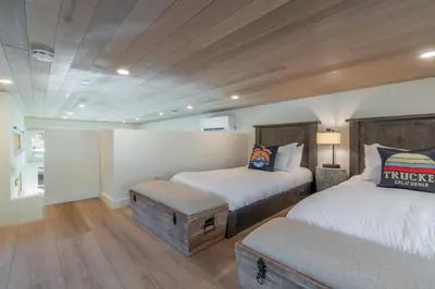 a bedroom with two beds and a bench in it at Village Camp Truckee in Truckee