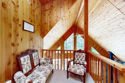 a room with two chairs and a staircase in a cabin at Cozy Chalet in Arnold