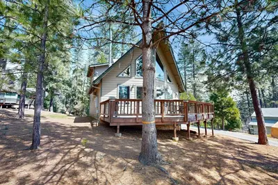 a house with a large deck in the woods at Cozy Chalet in Arnold