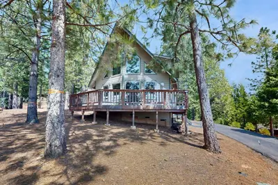 a house with a deck in the middle of trees at Cozy Chalet in Arnold