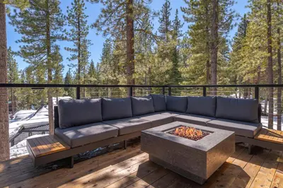 a couch sitting on a deck with a fire pit at Modern Eco Retreat with Hot Tub and Views in Truckee