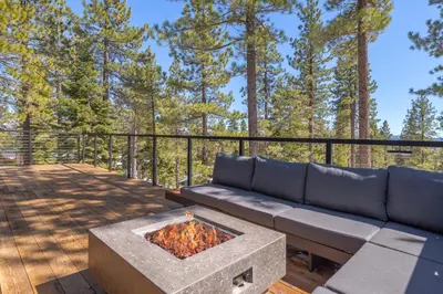 a couch sitting on a deck with a fire pit at Modern Eco Retreat with Hot Tub and Views in Truckee