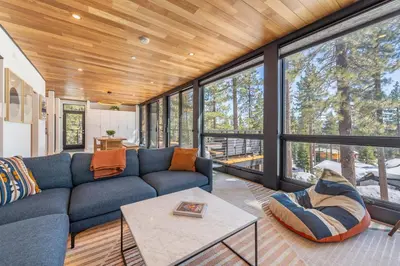 a living room with a blue couch and large windows at Modern Eco Retreat with Hot Tub and Views in Truckee