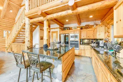 a large kitchen with wooden cabinets and a staircase at Mountain Cabin with Hot Tub 4 Mi to Shaver Lake! in Shaver Lake