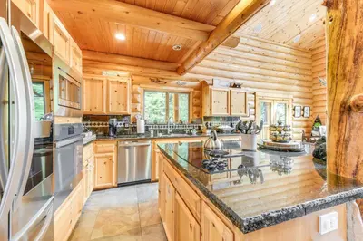 a large kitchen with wooden cabinets and a refrigerator at Mountain Cabin with Hot Tub 4 Mi to Shaver Lake! in Shaver Lake