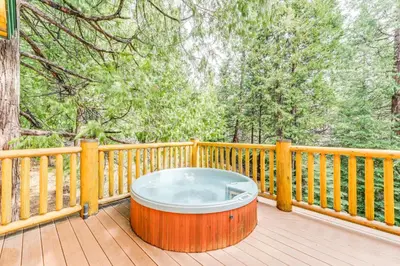 a hot tub sitting on a deck on a porch at Mountain Cabin with Hot Tub 4 Mi to Shaver Lake! in Shaver Lake