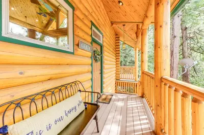 a log cabin porch with a bench and windows at Mountain Cabin with Hot Tub 4 Mi to Shaver Lake! in Shaver Lake