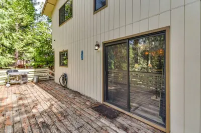 a house with a large glass door on a patio at 2 Mi to Mi-Wuk Village Cabin with Large Deck in Twain Harte