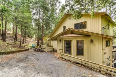 a house in the woods with a driveway at 2 Mi to Mi-Wuk Village Cabin with Large Deck in Twain Harte