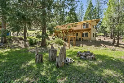 a house in the woods with a fence in front of it at The Cozy Cabin - 2-Level Home with Spacious Yard home in Groveland