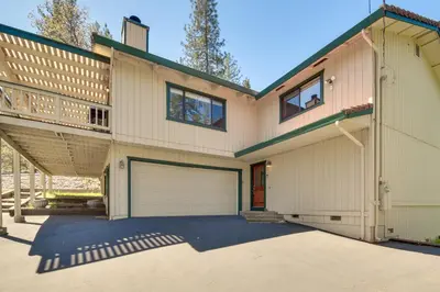 a house with a garage and a balcony at Cozy Cabin in Pine Mountain Lake Near Yosemite! in Groveland