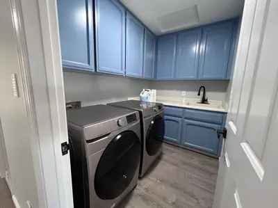 a small kitchen with blue cabinets and a washing machine at Entire 3 BR & 2 BA house for business and family in Modesto