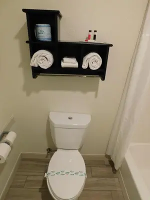 a bathroom with a toilet and towels on a shelf at Travelodge by Wyndham Angels Camp CA in Angels Camp
