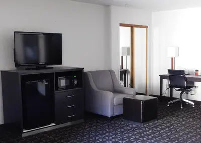 a living room with a tv and a chair and a desk at Travelodge by Wyndham Angels Camp CA in Angels Camp