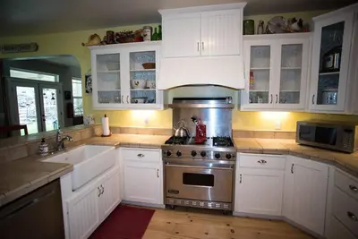 a kitchen with white cabinets and a stove and a sink at Yosemite Firehouse Inn in Mariposa