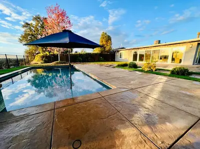 a swimming pool with an umbrella in front of a house at Sunrise View in Rocklin