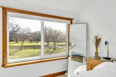 a bedroom with a window with a view of a field at Lakeside Vineyard Retreat - Deaver's Winery in Plymouth