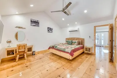 a bedroom with a bed and a wooden floor at #4 Cottage Like Suite with Private Hot Tub in Bass Lake