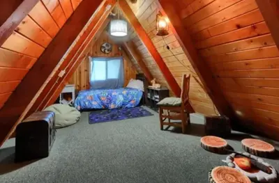 a room with a bed and a desk in a attic at Knotty Pines Lodge in Bass Lake Annex