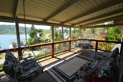 a porch with chairs and a table and a view of the water at Fox Lake View in Bass Lake