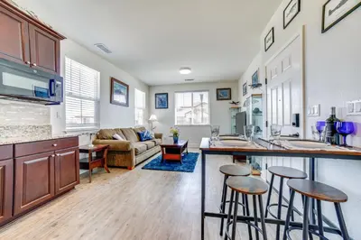 a kitchen and living room with a counter and stools at WWII Aviation-Themed Apt in Sparks Near Parks! in Sparks