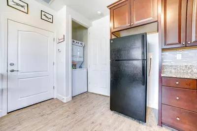 a kitchen with a black refrigerator and wooden cabinets at WWII Aviation-Themed Apt in Sparks Near Parks! in Sparks