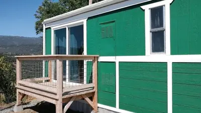 a green and white tiny house with a porch at Mystic Mountain Retreat in Miramonte