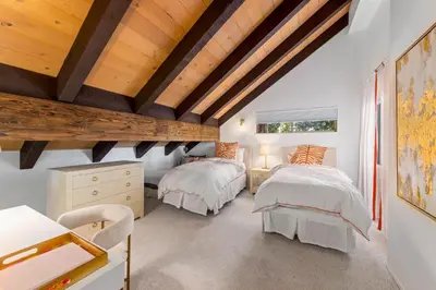 two beds in a room with wooden ceilings at Towering Pines Lakefront - 3 BR w Hot Tub & Buoy in Tahoe City