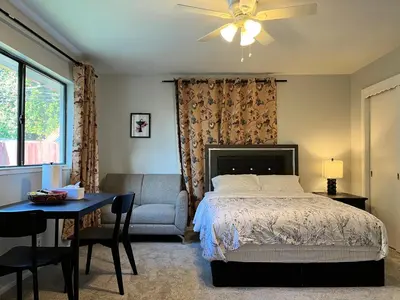 a bedroom with a bed and a chair and a table at Cozy Suite with Private Patio Close to Downtown and UC Davis Medical Center in Sacramento