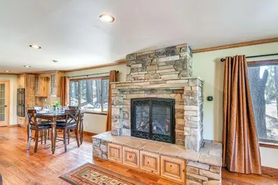 a living room with a stone fireplace and a table at 1 Mi to Ski Resort South Lake Tahoe Townhome in South Lake Tahoe