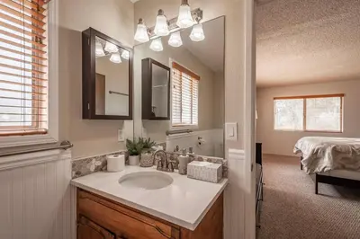 a bathroom with a sink and a mirror and a bed at Royal Arches Cottages in Oakhurst