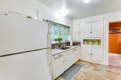 a kitchen with white cabinets and a refrigerator at 8 Mi to Yosemite National Park Cabin with Fire Pit in Oakhurst