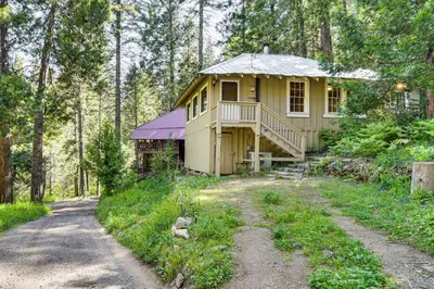 a house in the woods with a dirt road in front at 8 Mi to Yosemite National Park Cabin with Fire Pit in Oakhurst