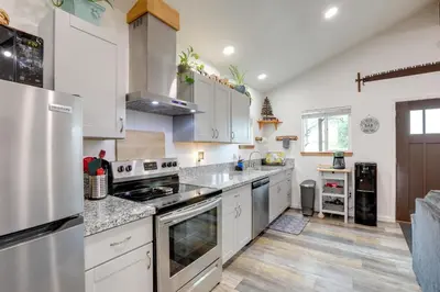 a kitchen with white cabinets and stainless steel appliances at Cozy Cottage with Park Pass, 1 Mi to Jenkinson Lake! in Pollock Pines