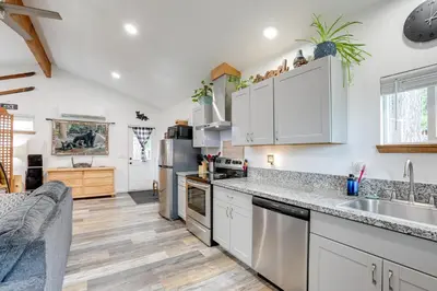 a kitchen with white cabinets and stainless steel appliances at Cozy Cottage with Park Pass, 1 Mi to Jenkinson Lake! in Pollock Pines
